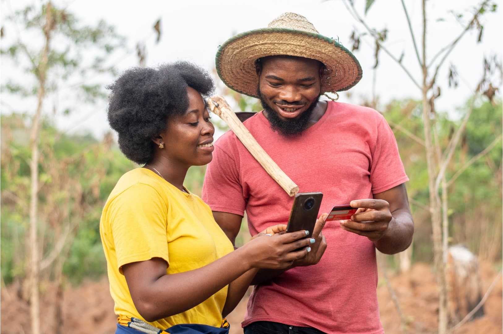A farmer couple checking a phone and a payment card in their field
