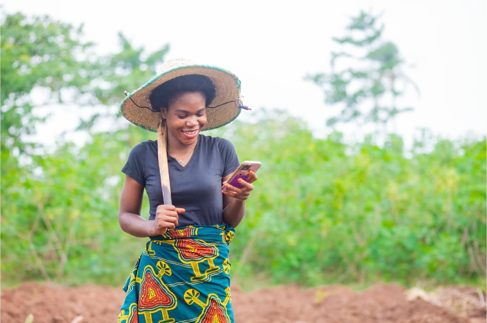 A smallholder farmer checking her phone in the field